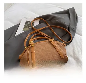Detail view of the brown woven canvas bag with leather trim and gold hardware on a suit