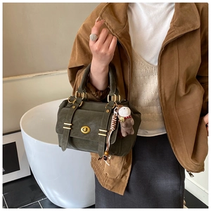 Detail of dark green retro crossbody bag with gold lock and brown teddy bear charm