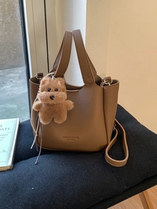Brown litchi grain leather bucket bag with top handle and cute puppy charm accessory