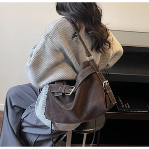 Detailed view of dark brown vintage leather tote with silver buckle on female model