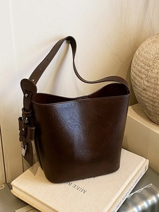 Retro dark brown leather underarm bag with metal padlock and adjustable strap on book