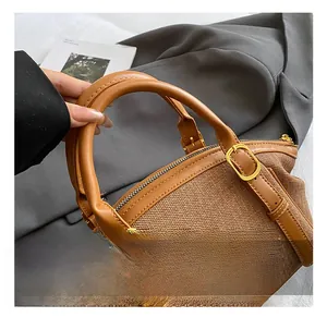 Close-up of brown textured woven handbag with leather straps and gold metal hardware