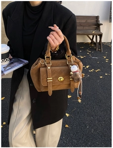 Detail of vintage brown suede crossbody bag with gold twist lock and horse charm