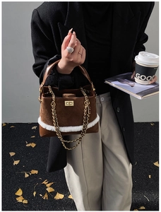 Close-up of caramel suede handbag featuring white faux fur trim and gold chain detail