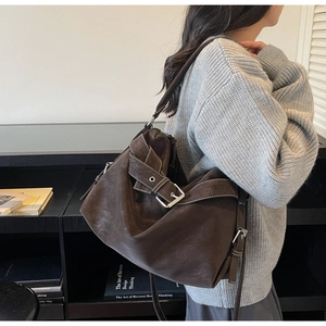 Close-up of vintage brown tote bag with contrast stitching and decorative metal buckles