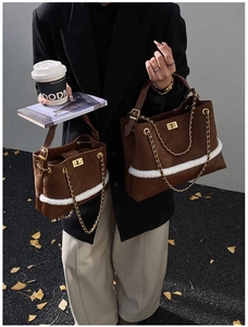 Close-up of brown suede tote bag featuring white faux fur trim and gold chain detail