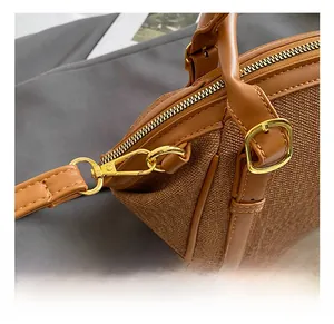 Detailed close-up of brown woven canvas bag with golden hardware and leather trim