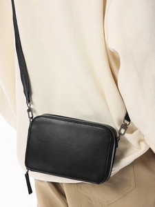 Minimalist black rectangular crossbody bag with adjustable strap and silver zipper closure