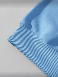 Close-up of light blue rib-knit cuffs on a loose sweatshirt with detailed fabric texture