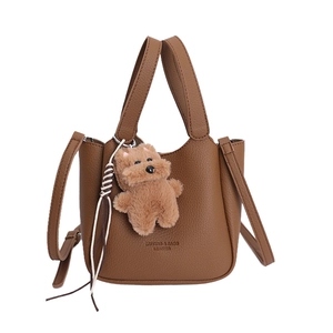 Brown lychee leather bucket bag with plush bear charm and dual shoulder straps