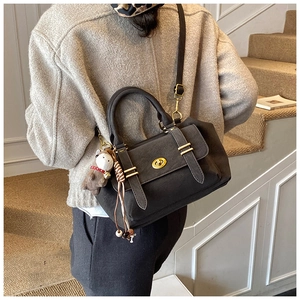 Detail of dark gray matte crossbody bag with golden lock and cute plush bear charm