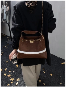Detail of dark brown suede shoulder bag with white faux fur trim and gold chain strap