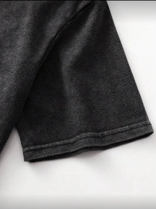 Detailed macro view of the double-stitched hem on a washed charcoal grey cotton t-shirt