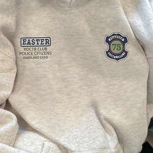 Détails de l'écusson vintage et de l'imprimé sur le sweat à capuche gris clair