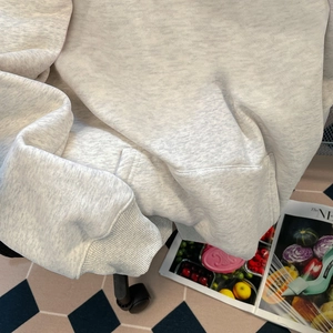 Détail du sweat à capuche gris montrant le poignet côtelé et la texture douce en maille