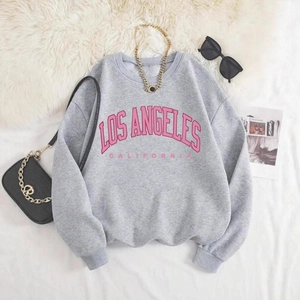 Mise à plat d'un sweat gris avec texte Los Angeles rose sur tapis blanc doux