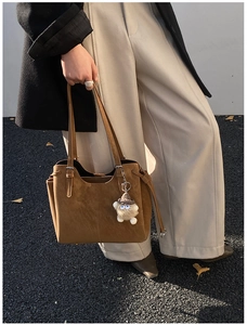 Detail of warm brown suede tote bag with slim straps and cute plush eye charm