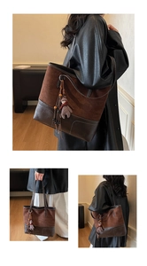 Detailed view of women's suede tote bag with bear charm and spacious interior design.