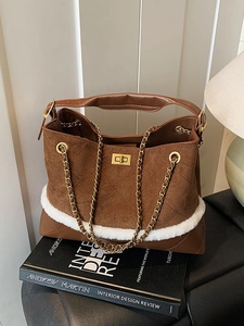 Retro suede hobo bag with quilted stitching, chain strap and faux fur trim on a book