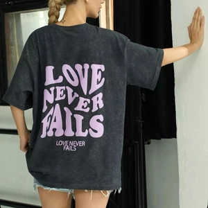 Detail view of the purple Love Never Fails print on acid wash charcoal cotton t-shirt