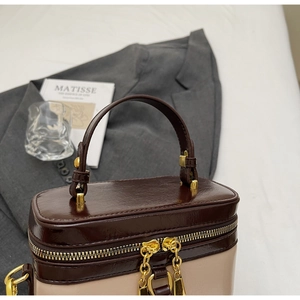 Nahaufnahme der zweifarbigen Retro-Box-Tasche mit braunem Griff und goldenem Reißverschluss