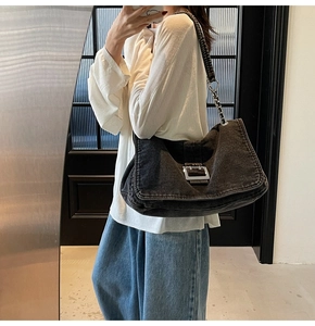 Détail du sac cabas en denim noir avec boucle métallique et bandoulière chaîne