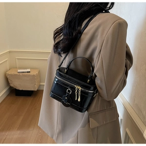 Model mit einer schwarzen glänzenden Kosmetiktasche mit Gold-Zippern im gemütlichen Raum