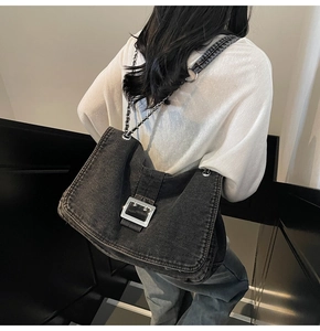 Gros plan d'un sac à bandoulière en denim noir vieilli avec boucle argentée et chaîne