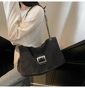 Détail d'un sac à bandoulière en denim noir avec boucle argentée et chaîne en métal chic