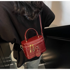 Detailaufnahme der burgunderroten Box-Handtasche mit goldfarbenen Reißverschlussdetails
