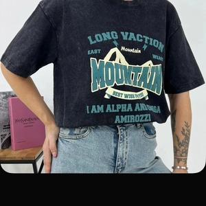 Detail of vintage washed black oversized t-shirt with teal mountain graphic print and text