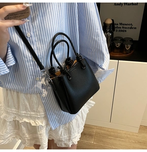 Gros plan du mini sac noir en cuir grainé avec un détail de poignée nouée élégant