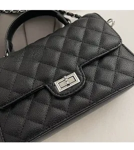 Detail of pebbled leather texture and metal twist lock on black quilted crossbody bag