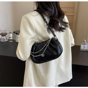 Detail of black pleated cloud bag with silver heart chain and woven shoulder strap
