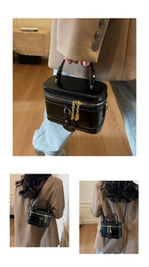 Details einer schwarzen Lackleder-Box-Tasche mit goldenen Reißverschlüssen und Griff