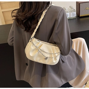 Detail of cream pleated cloud bag with silver heart chain and woven shoulder strap