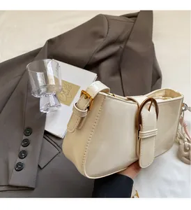 Close-up of beige glossy leather underarm bag with vintage bronze buckle in lifestyle setting