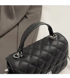 Detail of lychee pattern leather handbag handle with silver metal rings and quilting