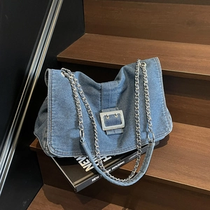 Sac à bandoulière en jean bleu avec boucle argentée sur fond d'escalier en bois