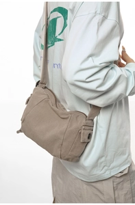 Vue latérale d'un sac bandoulière en toile kaki avec poche à bouton-pression et détails de sangle