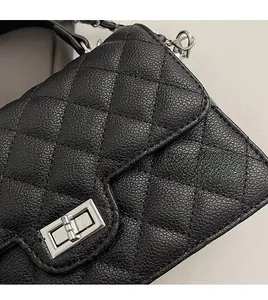 Detail of silver twist lock and quilted diamond pattern on black pebble leather bag