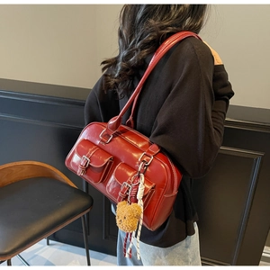 Detail view of burgundy glossy shoulder bag with twin front pockets and bear charm