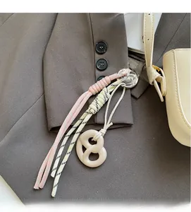 Detailed shot of pink and cream braided rope bag charm with resin twist ornament