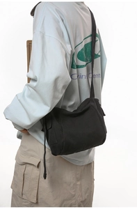 Detail shot of a black canvas crossbody bag featuring a wide strap and minimalist design