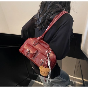 Detail of burgundy PU leather underarm bag featuring white contrast stitching and bear charm