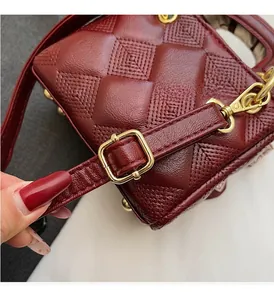 Close-up of wine red crossbody bag featuring luxury diamond quilted texture and gold hardware