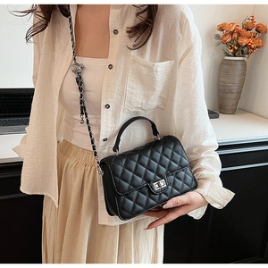 Detailed view of black quilted crossbody bag featuring silver metal turn-lock and chain strap