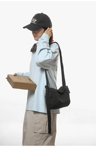 Vue latérale du sac bandoulière noir en toile avec poche, porté par le modèle au quotidien
