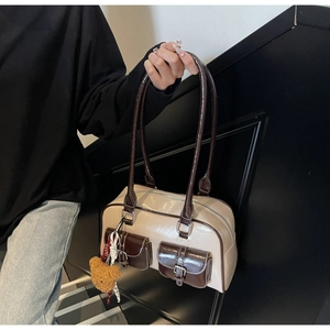 Close-up of contrast stitch shoulder bag with dual front pockets and a cute bear charm