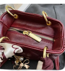Detail of smooth gold zipper and burgundy leather texture on a mini bucket bag